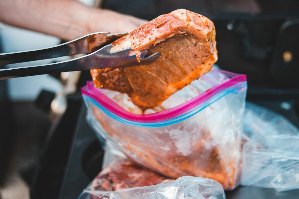 Person Putting a Marinated Pork Inside the Zip Lock