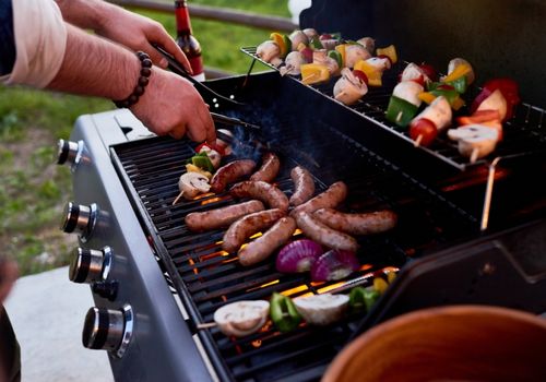 Person BBQing Veggies and Sausages