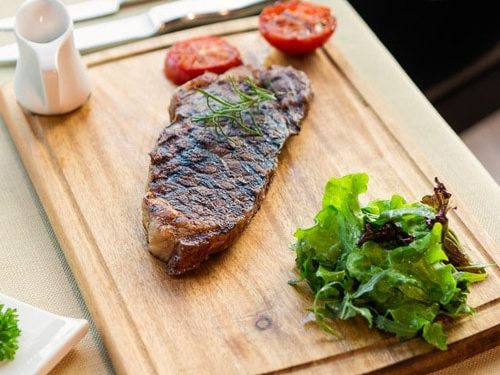 Tasty steak with vegetables on a wooden plate