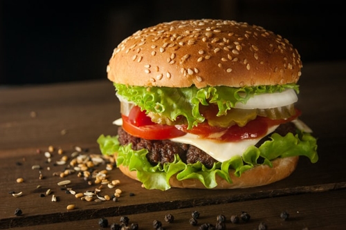 big burger on a wooden table with pepper and sesame