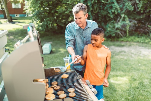 man showing his son how to bbq