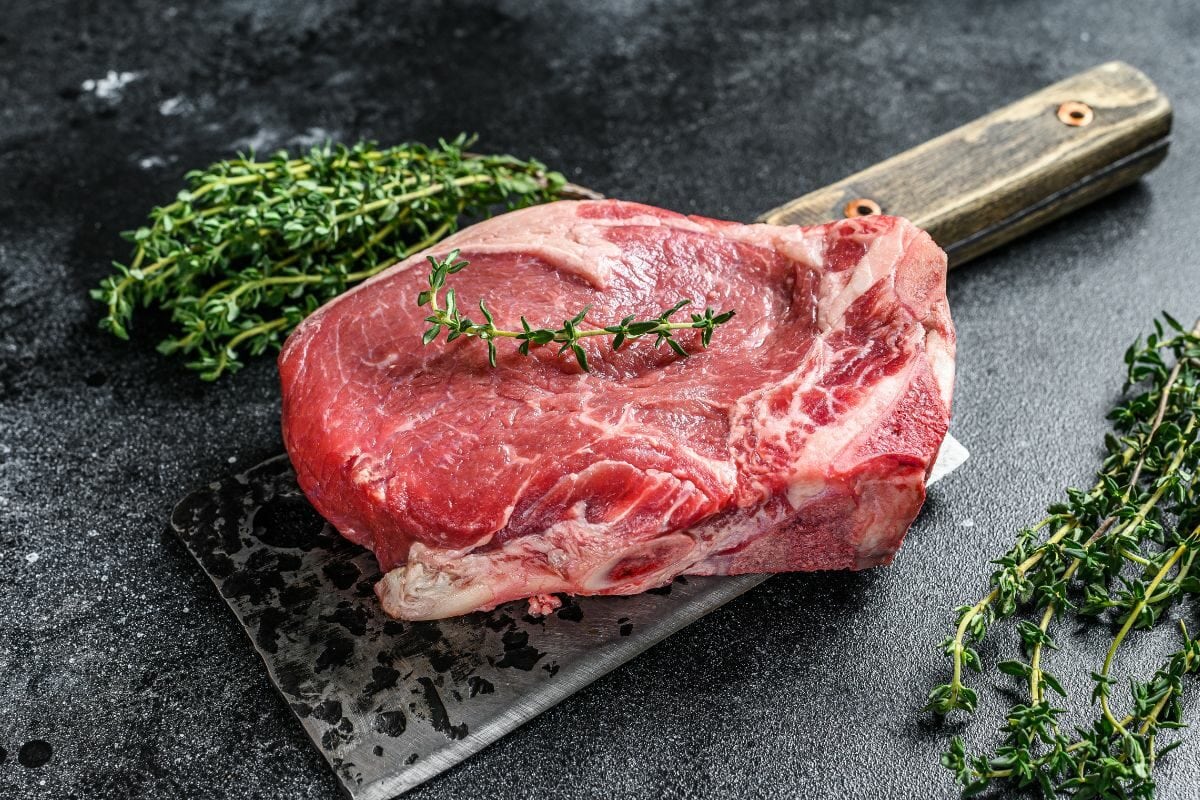 Well-Marbled Raw Steak with Herbs Placed on a Knife