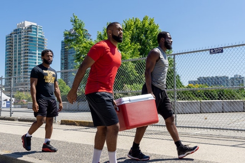 Men in Sportswear Carrying a Cooler while Walking