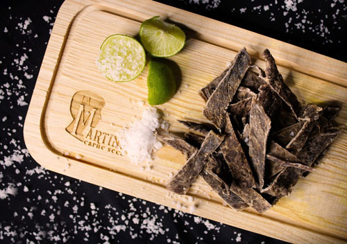 Slices of Meat on a Wooden Chopping Board with Lime and Salt