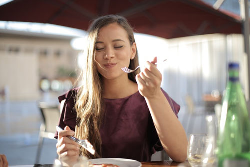 Woman Enjoying The Food At Restaurant