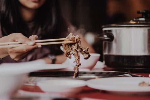 Woman Holding The Meat Using Chopsticks