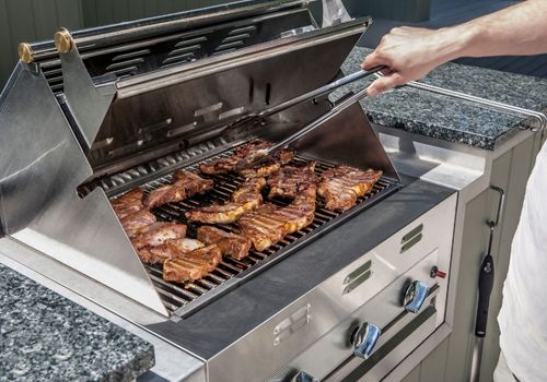 man grilling stakes on an outdoor propane gas grill