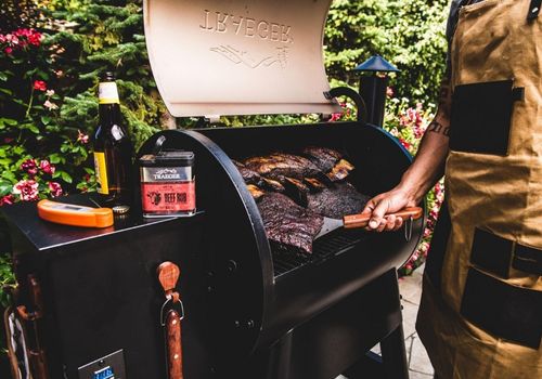 Person Smoking Meat Using Traeger Wood Pellet Grill