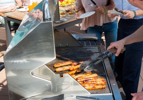 Person Grilling Sausages Using BBQ Grill