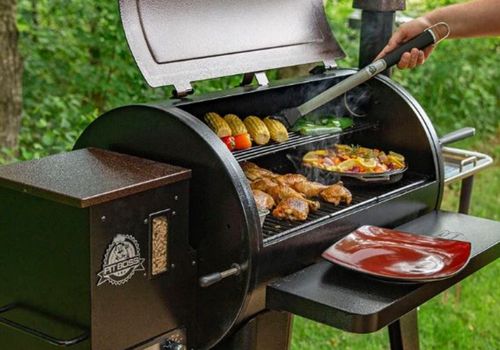 Person Grilling Using Pit Boss Mahogany Wood Pellet Grill
