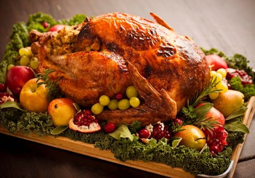 Roasted turkey on a wooden plate with pears, grapes and pomegranates