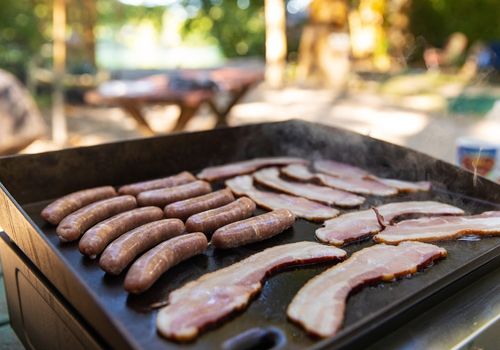 Bacon and Sausages are Grilled on a Flat Griddle
