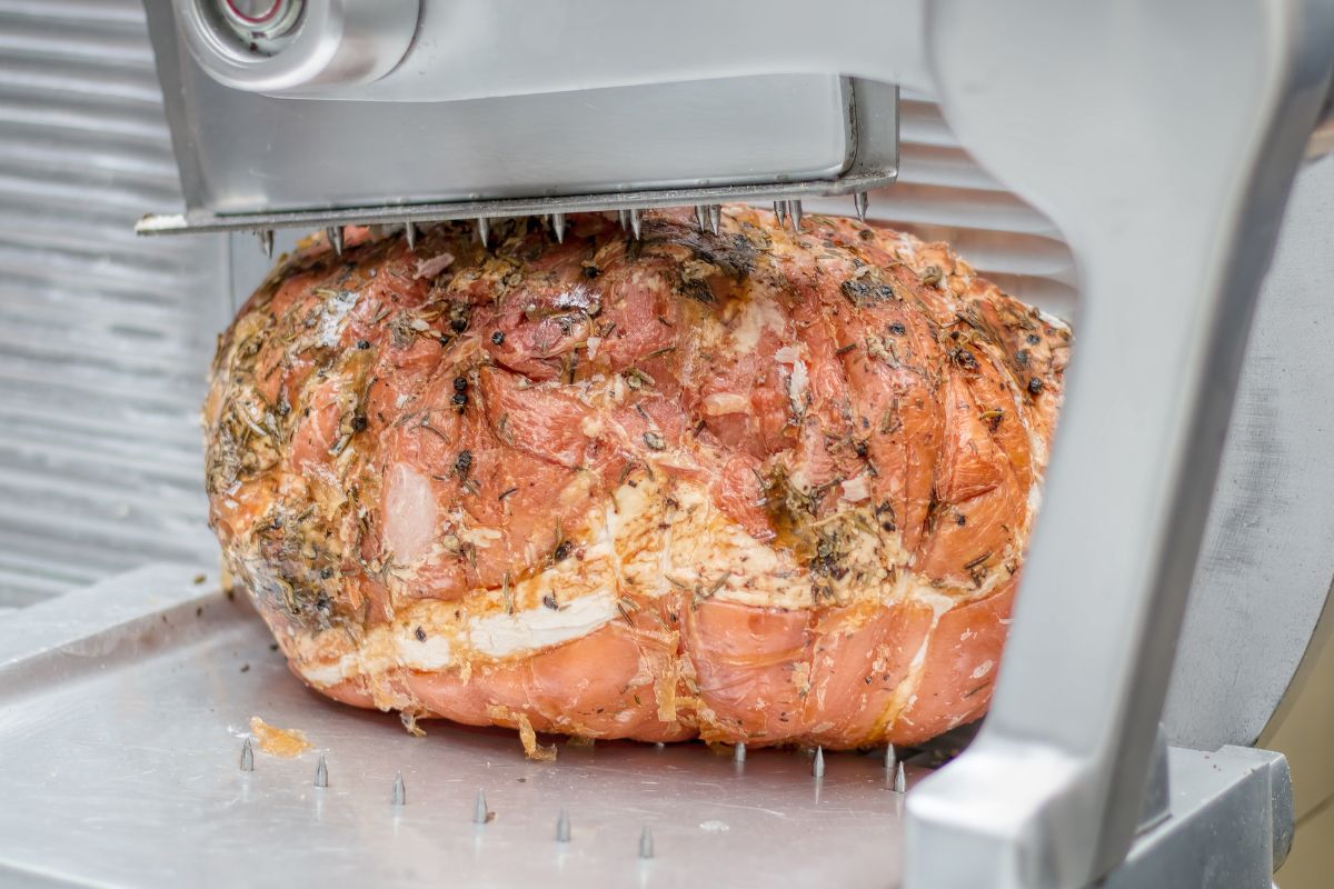 Cooked Cotto Ham with Herbs on the Meat Slicer