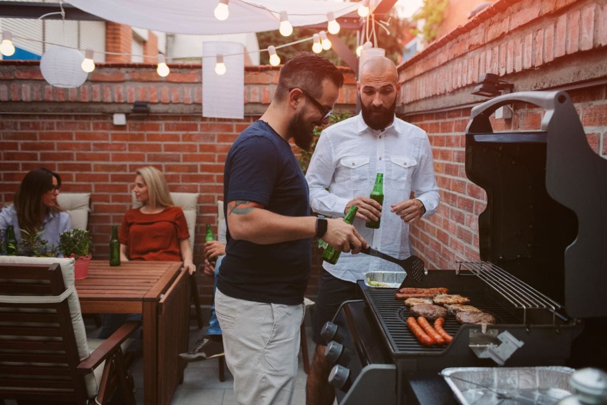 Two Men Chatting While Barbecuing Meat and Sausages
