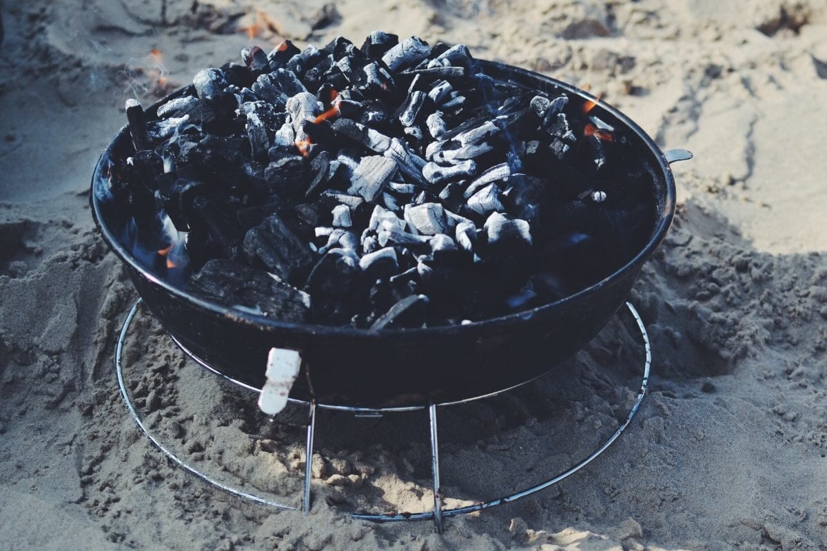 Black Fire Pit on the Sand with Burnt Charcoal