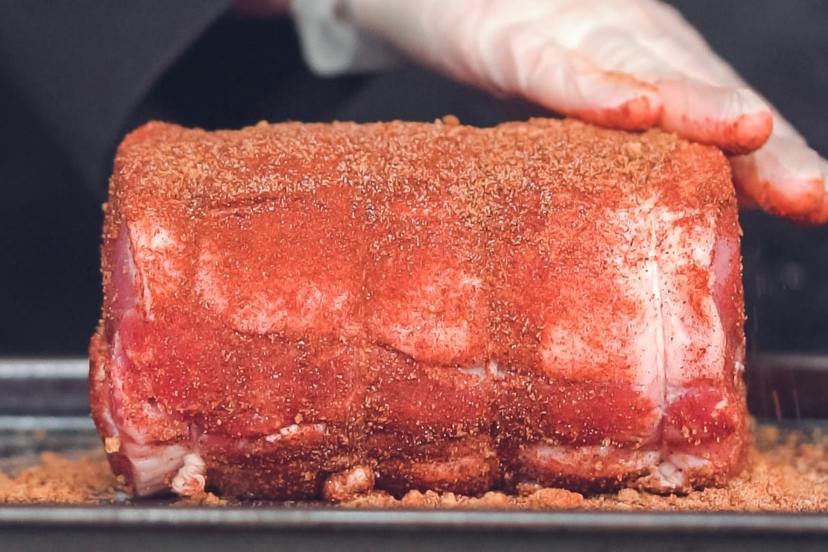 Chef Rubbing Spices Over Boneless Pork Roast
