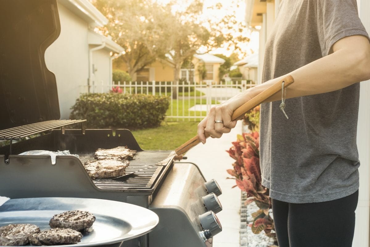 Person Cooking Steak, Burger Patties on a Gas Grill
